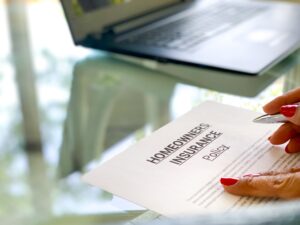 Woman reading a Homeowners Insurance Policy to be signed with laptop in background